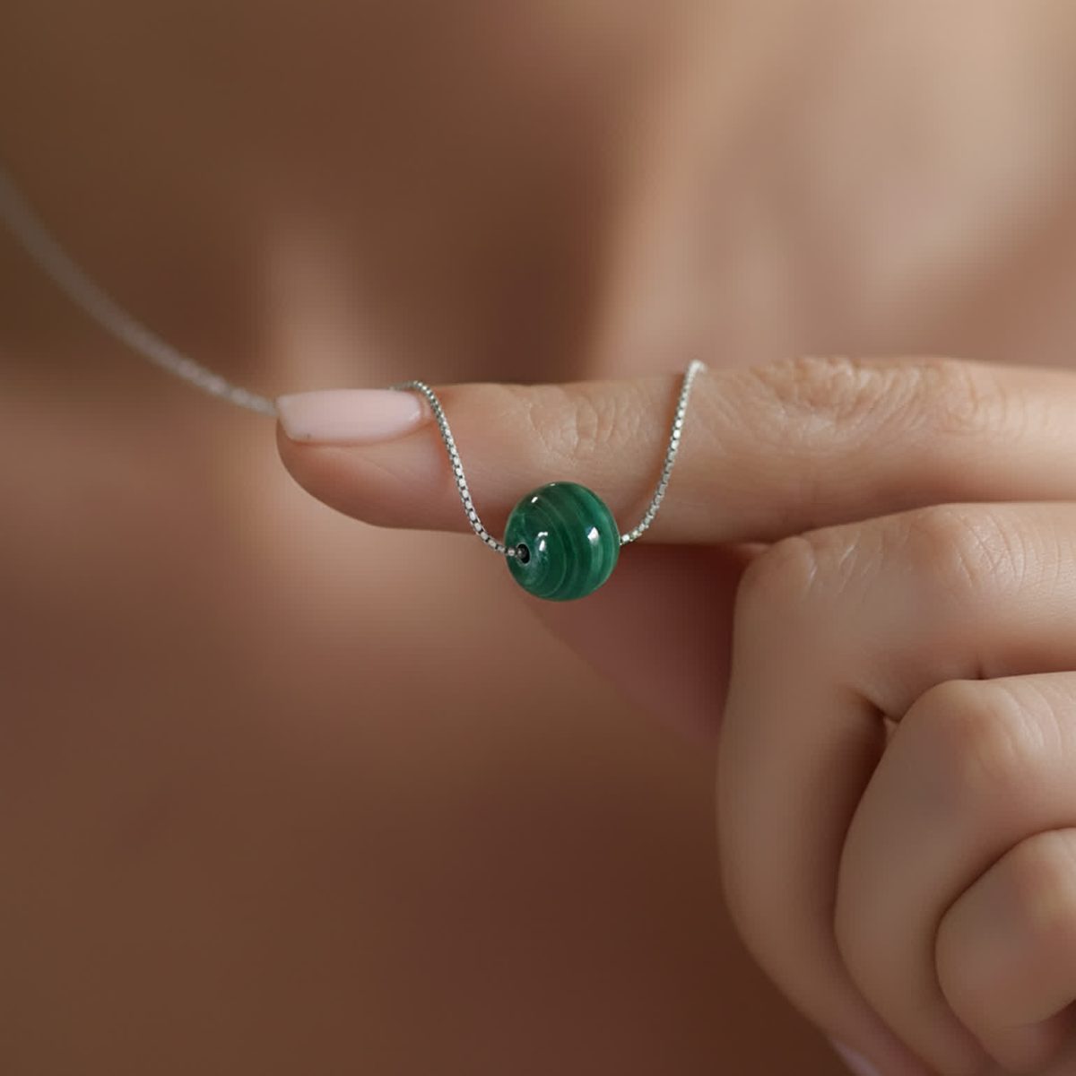 Dainty malachite bead necklace worn close to skin with simple gold-toned styling.