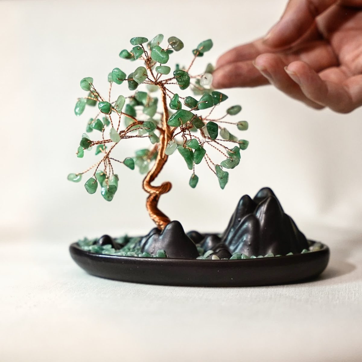 Close-up of polished jade crystal leaves on copper wire tree of life