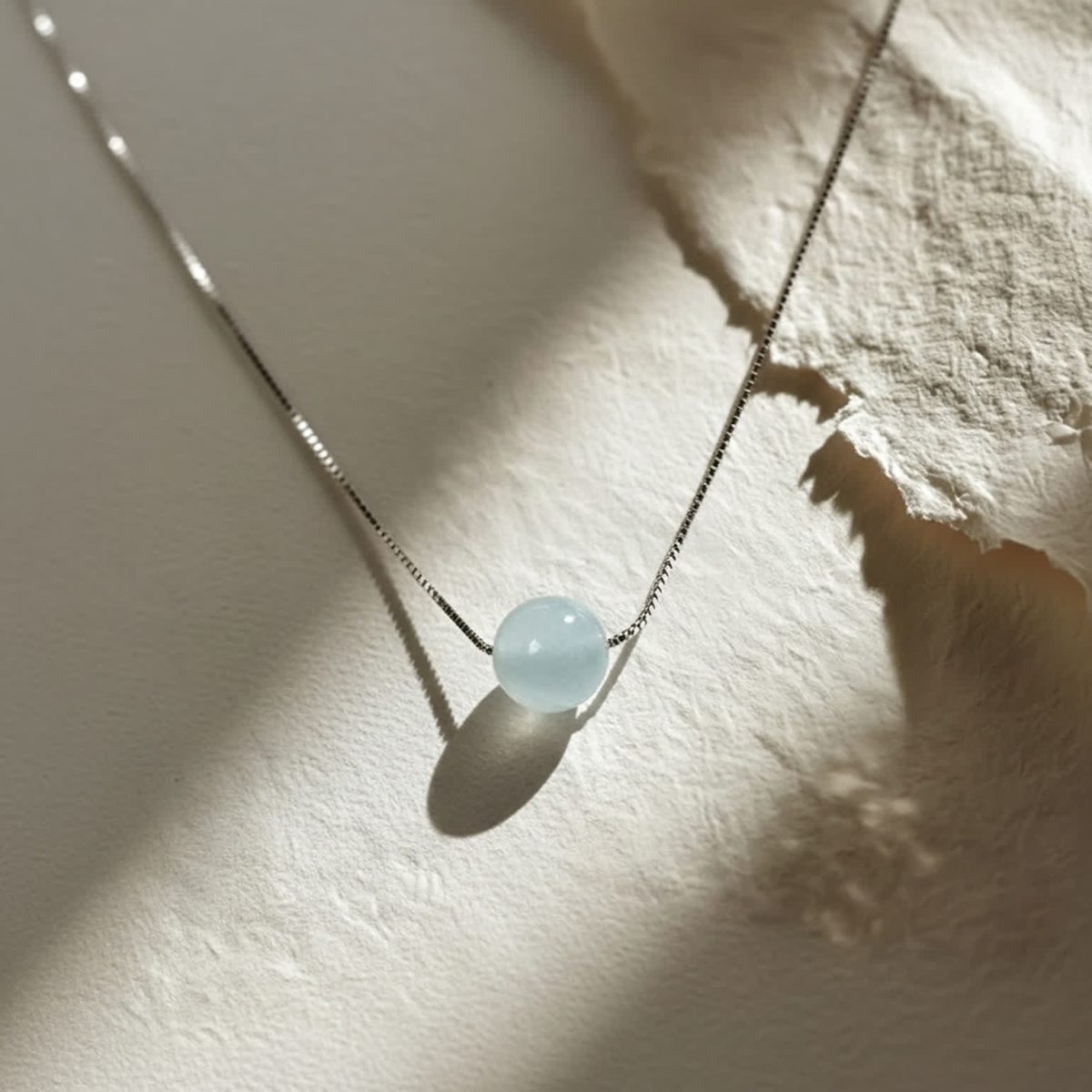 Aquamarine birthstone jewelry displayed on neutral textured surface
