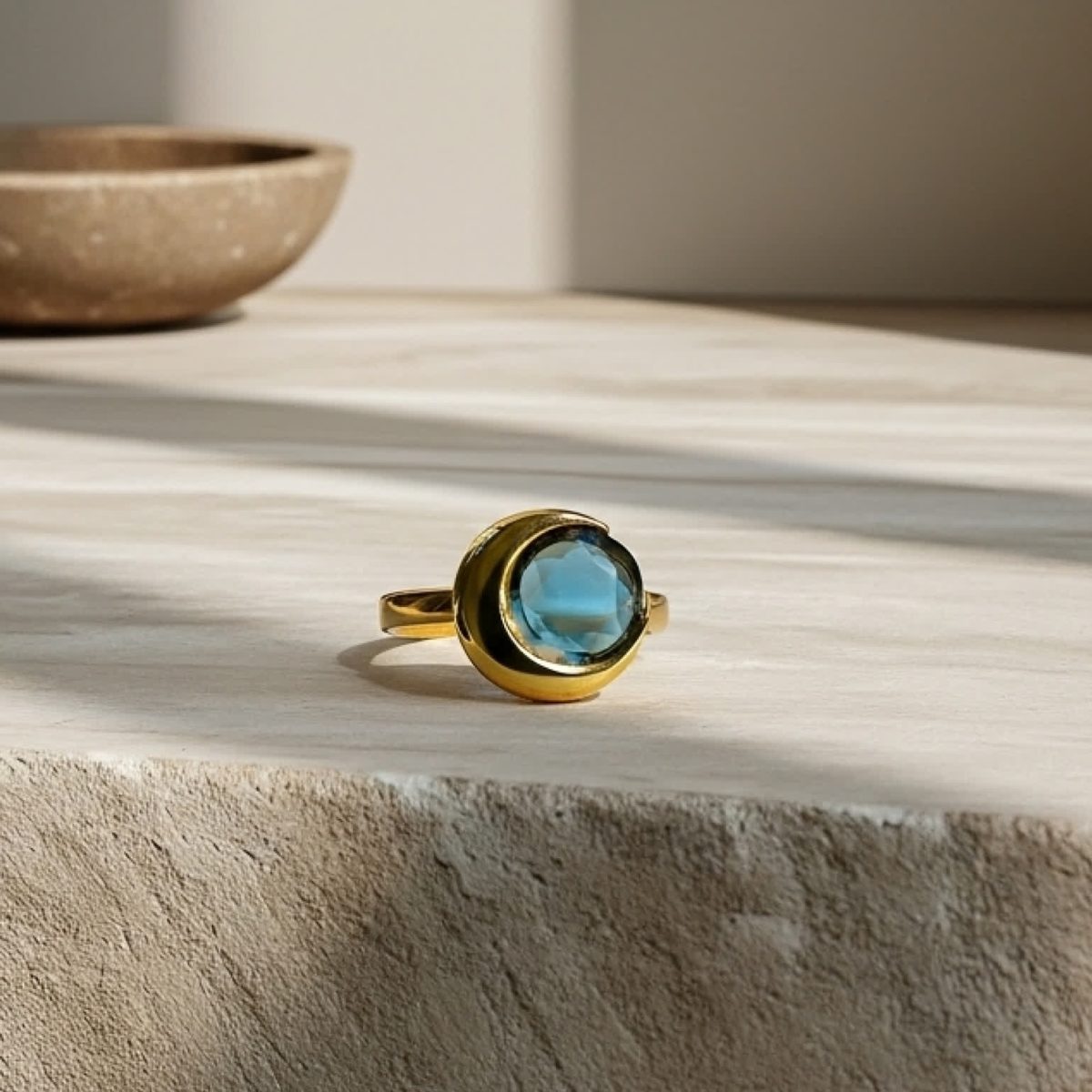 London blue topaz ring styled on stacked stone props with artisanal mood.