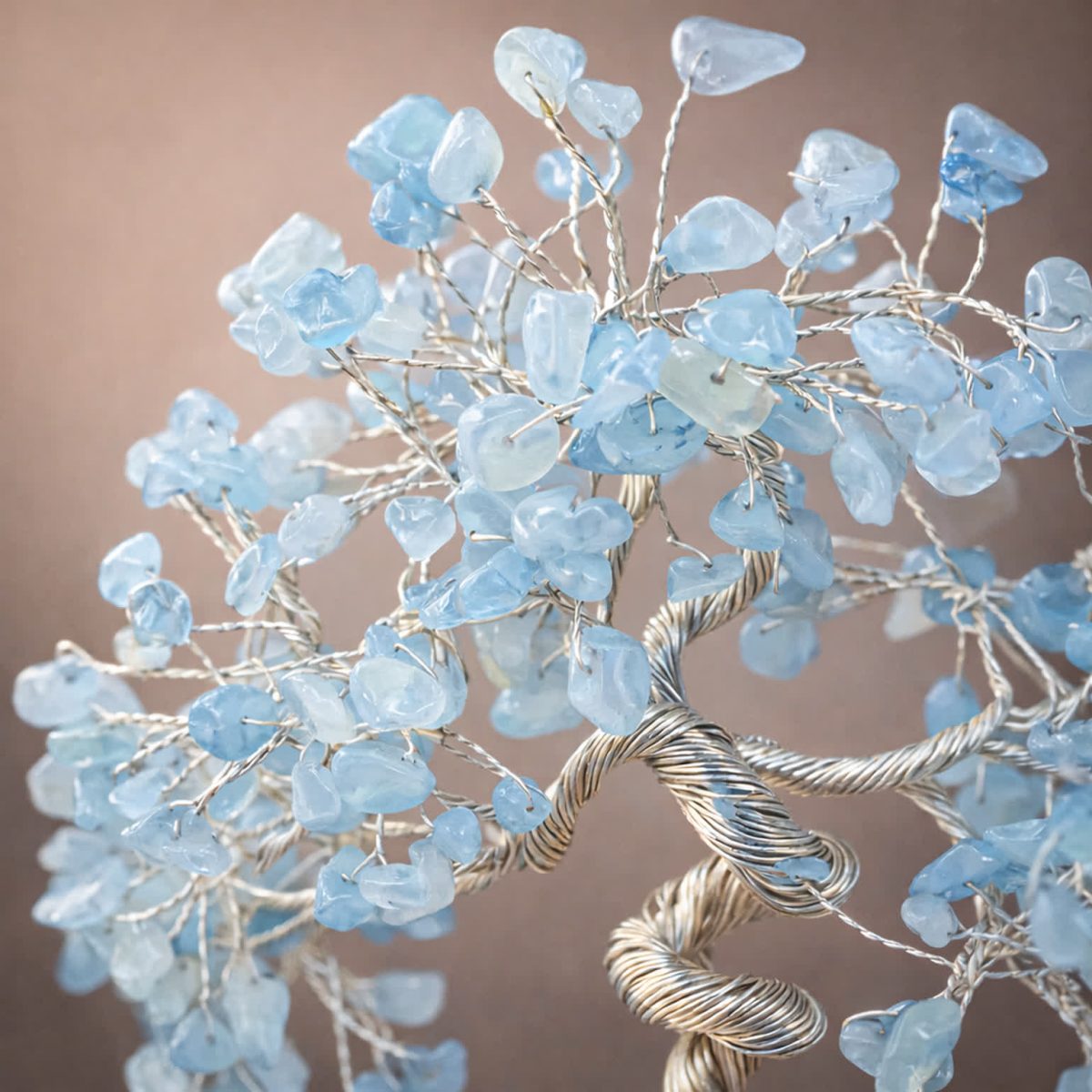Close-up of aquamarine crystal tree branches showing polished blue gemstone chips and silver wire detail