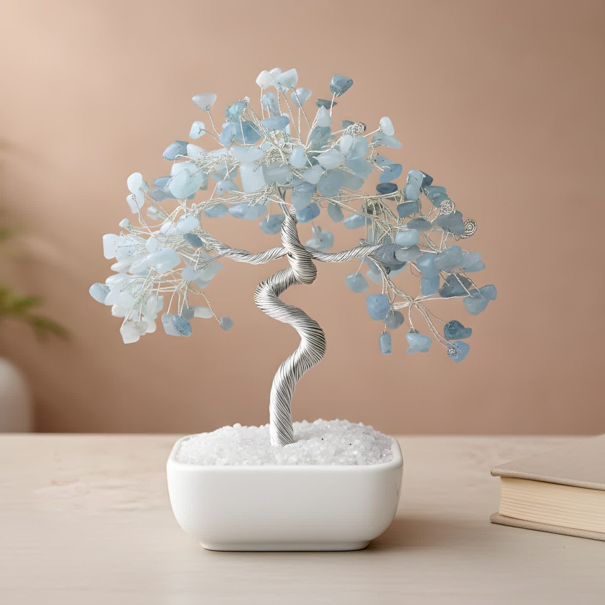 Aquamarine crystal tree bonsai with polished blue gemstone chips in a white ceramic base on a wooden surface