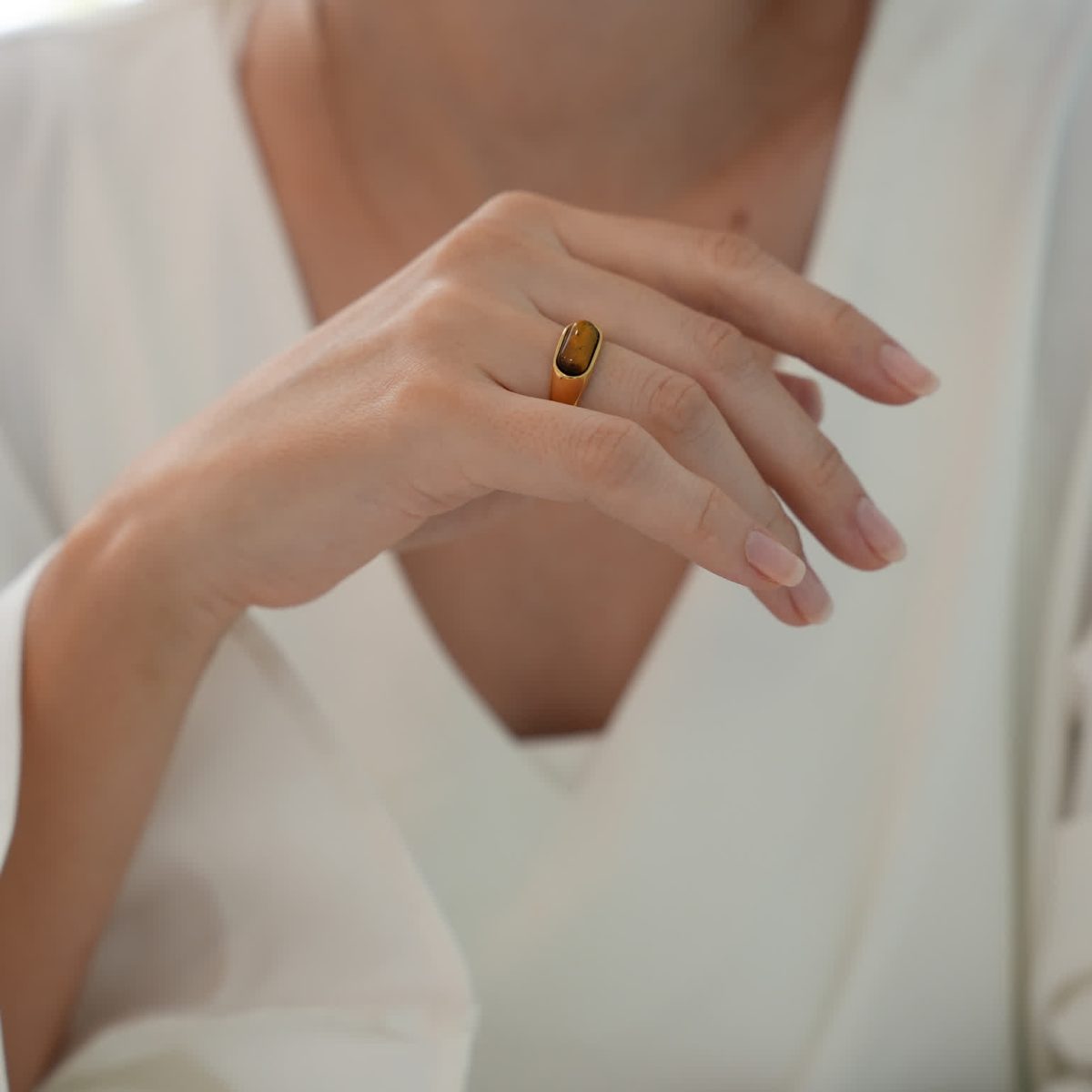 Sleek gold tiger eye ring shown on fingers in modern minimalist look.