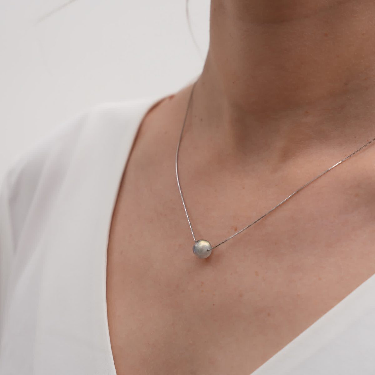 Close view of labradorite necklace silver on model wearing white blouse