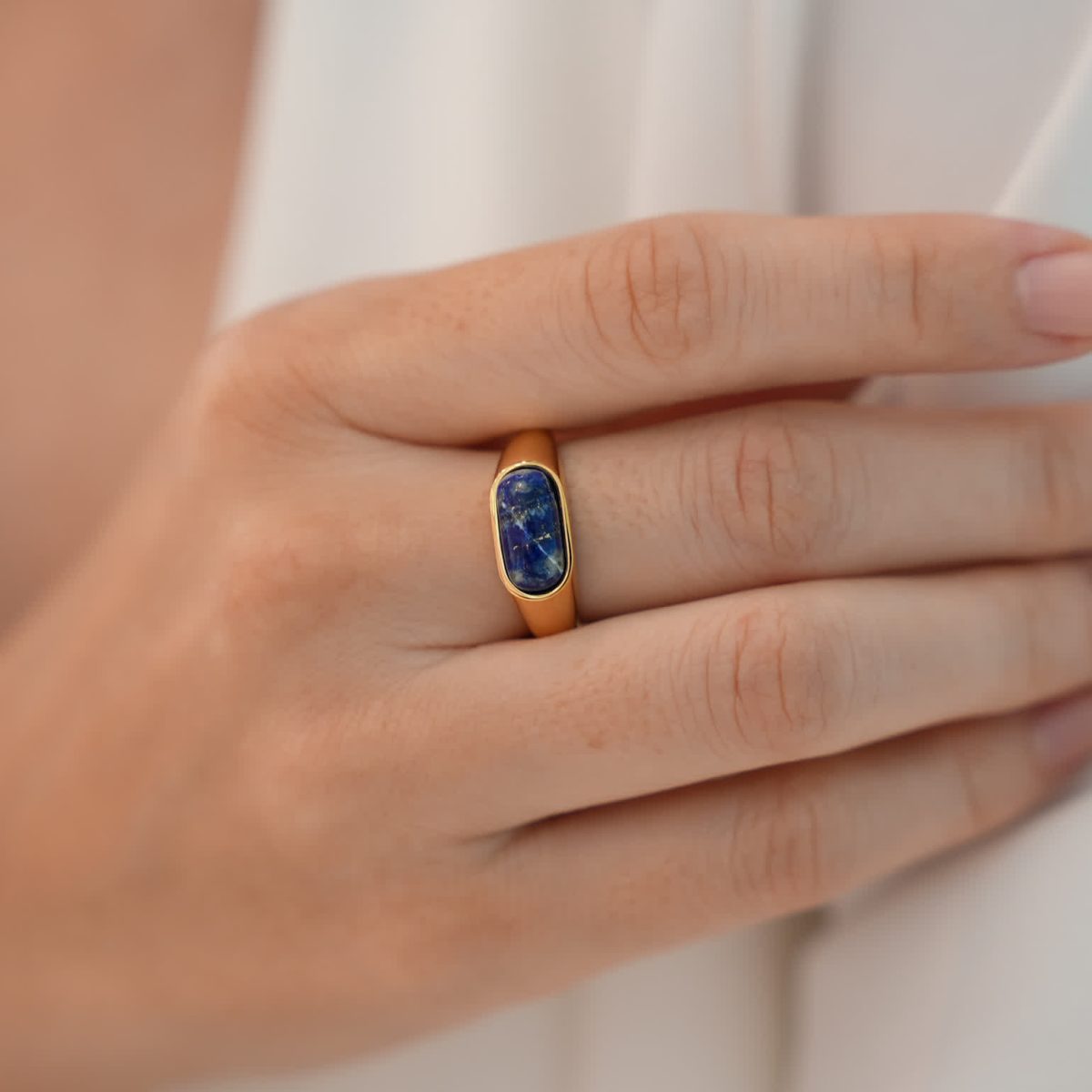 Minimalist blue stone ring styled on fingers with smooth gold plated stainless steel band.