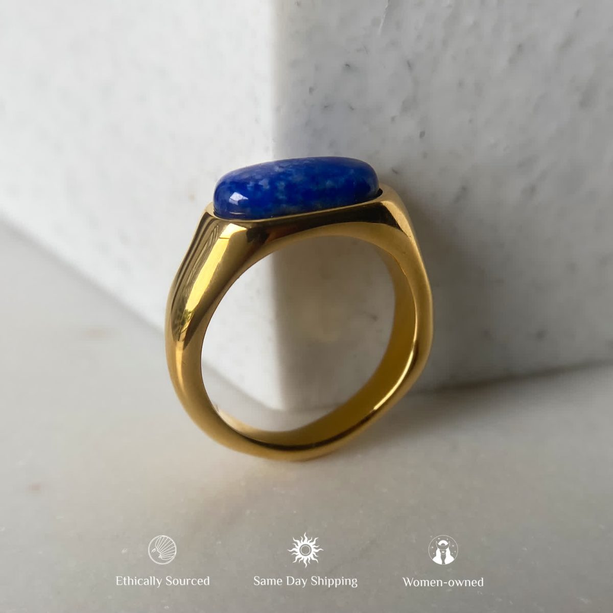 Gold plated lapis lazuli ring resting on soft fabric with visible polished surface.