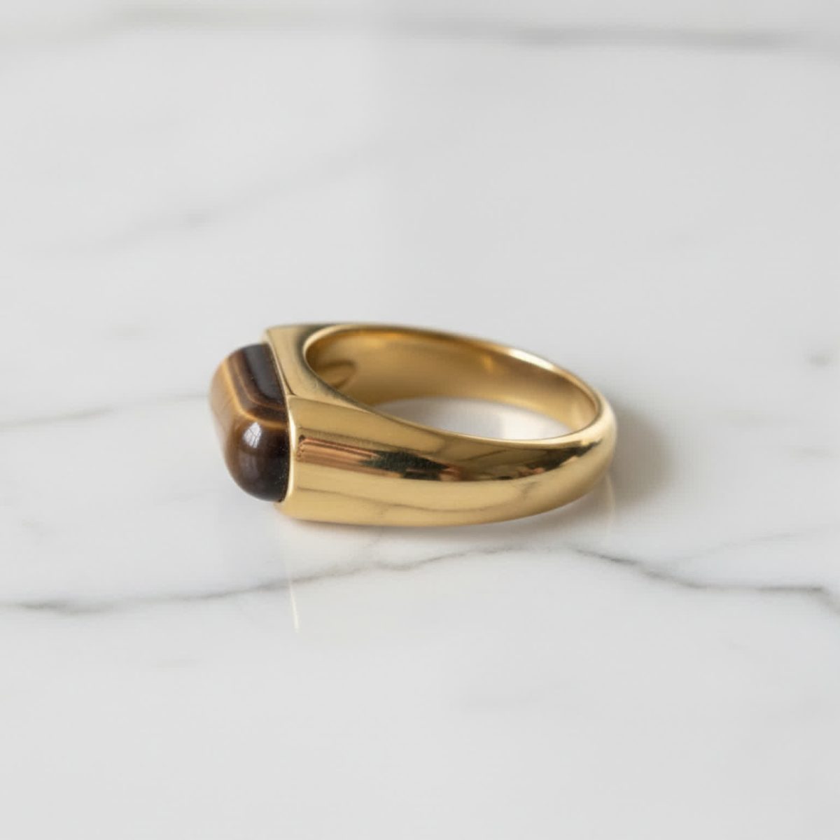 Side detail of tiger eye ring highlighting curved gold band and glossy stone.