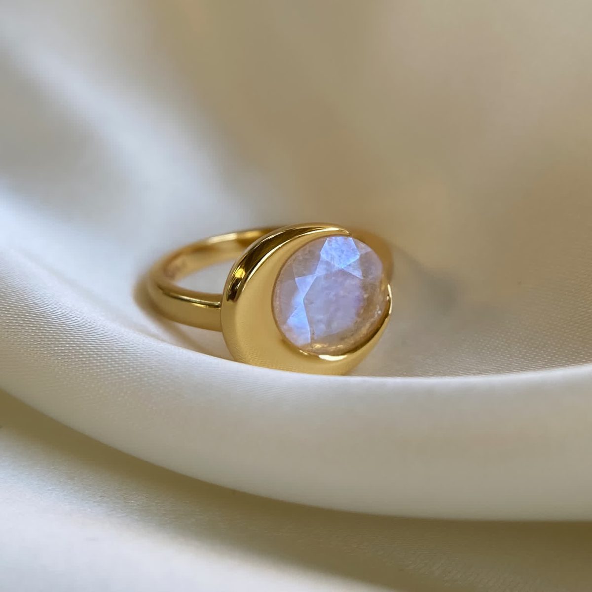 Moonstone ring photographed on soft fabric highlighting natural fogginess and glow.