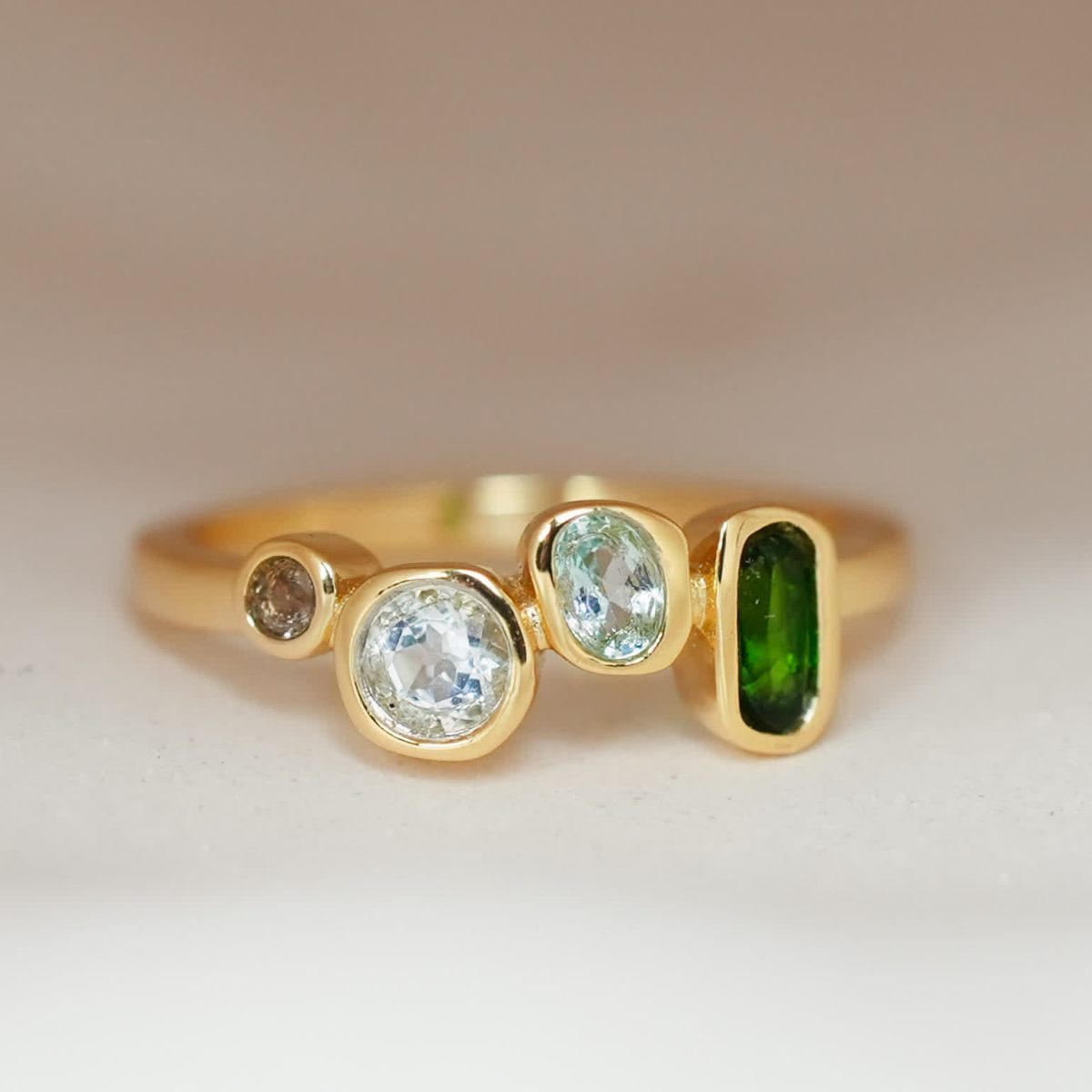 Front view of a multi-colored gemstone ring with emerald, topaz, and smoky quartz in gold plating.