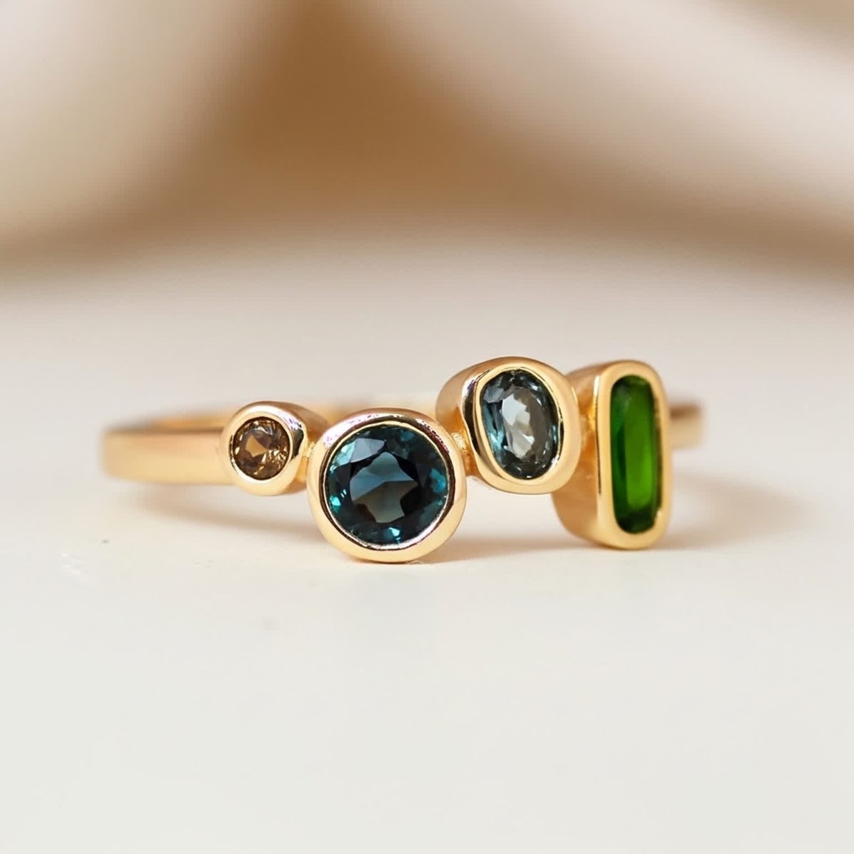 Front view of a london blue topaz ring with emerald, aquamarine, and smoky quartz set in gold.