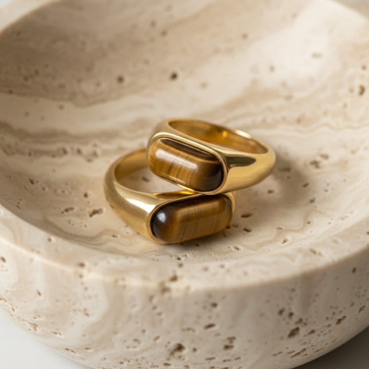 Close view of tiger eye ring worn on hand showing smooth brown stone and gold finish.